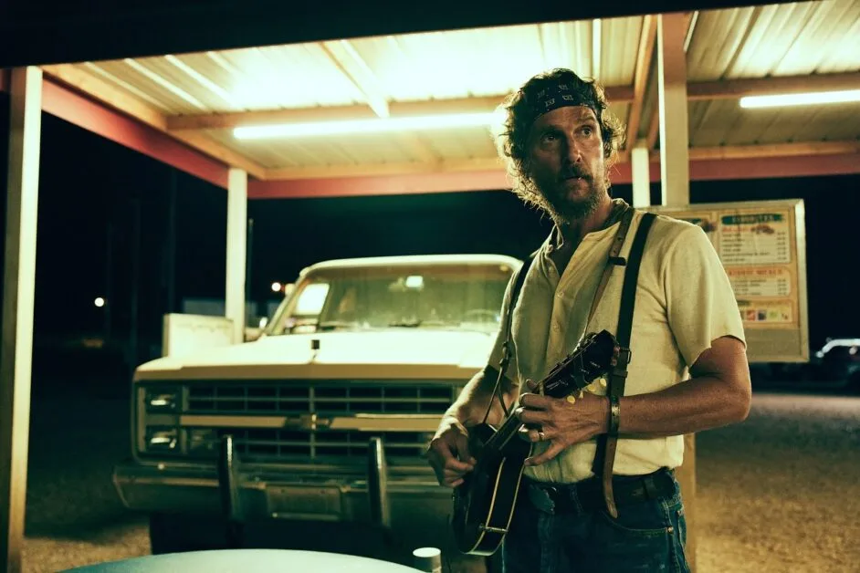 McConaughey with a banjo in a carhop parking area of a diner.