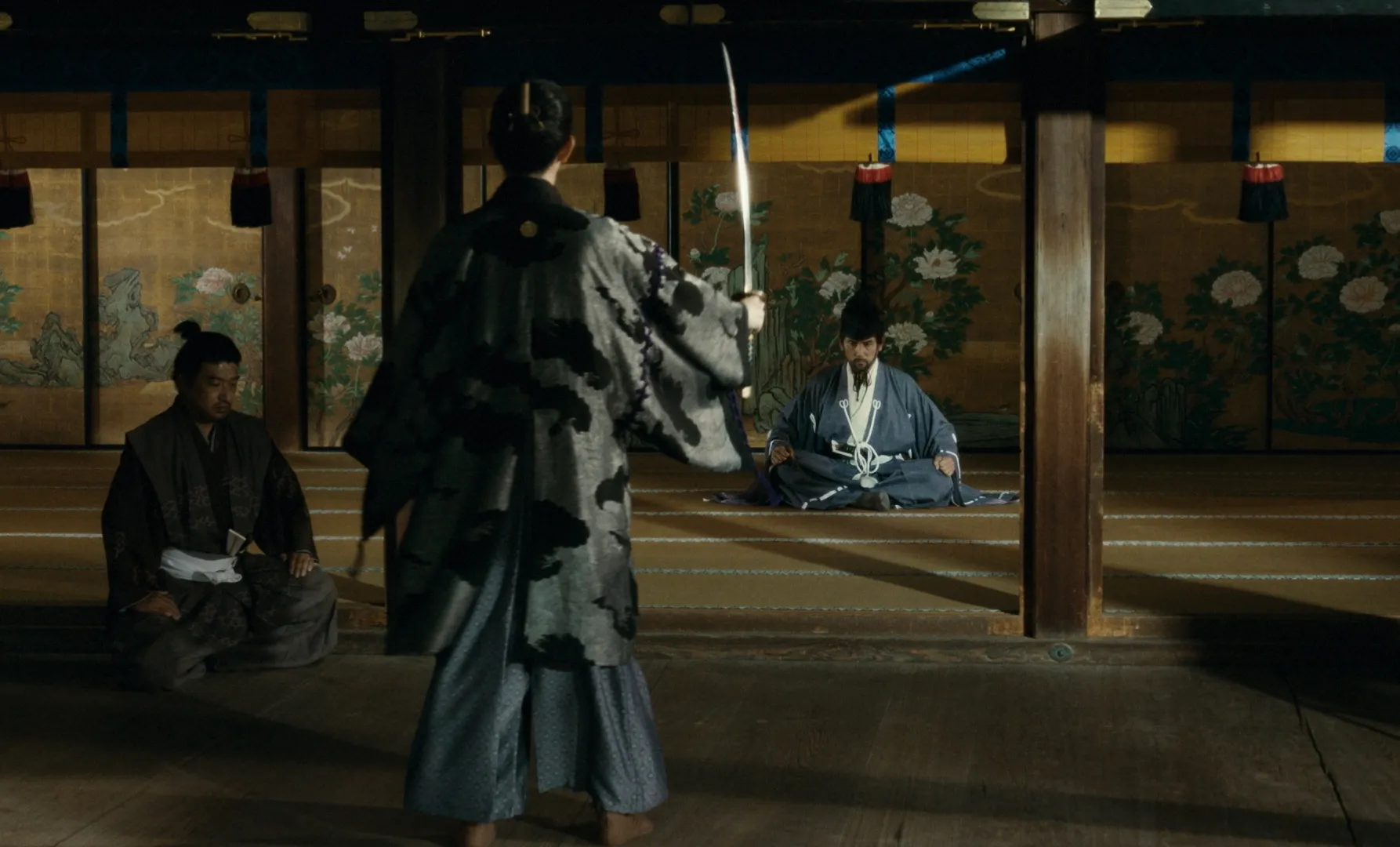 Figure with back to use holding sword in hand, facing a man seated Japanese style, and another man in formal sitting position off to one side.