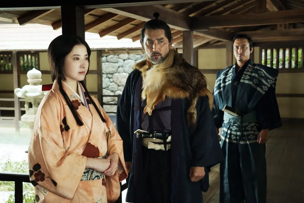 A man and two women in traditional costume in the atrium of a castle.