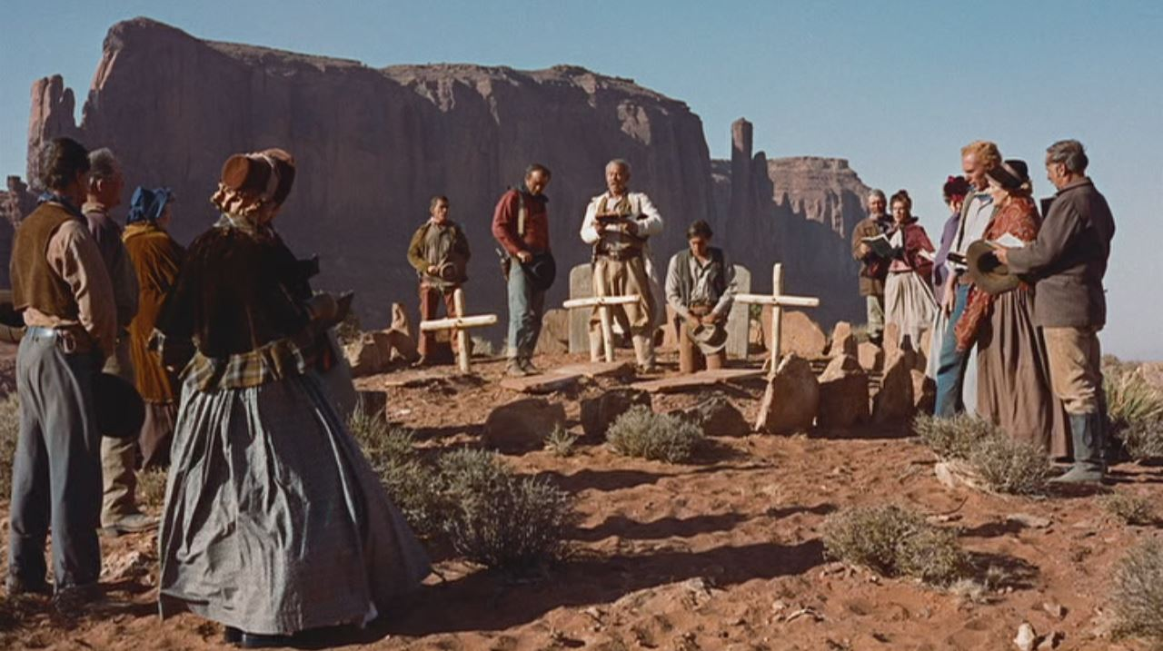 People standing around fresh graves.