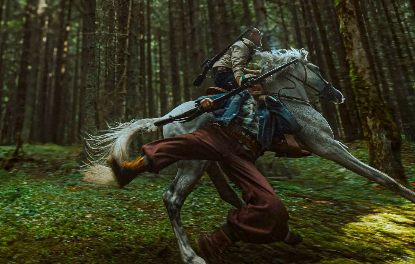 Guy with gun being carried off by guy on horse.